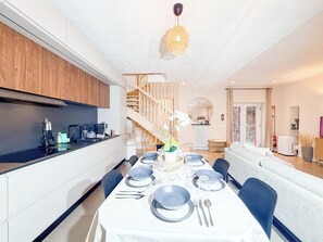 Una cocina moderna con comedor listo para una comida, que incluye una escalera y una sala de estar con sofá.