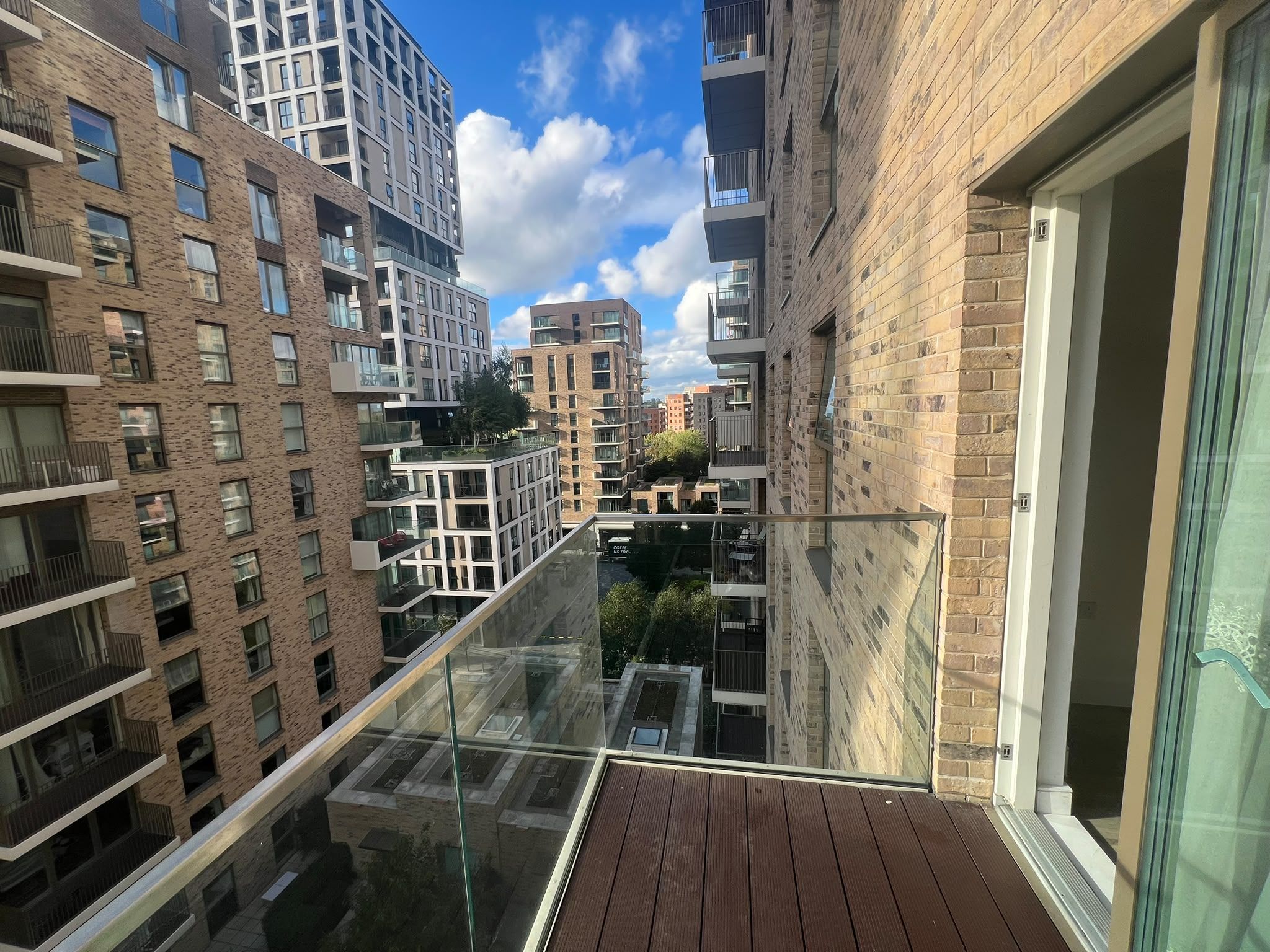 A high-rise building with multiple balconies and a glass railing overlooking a cityscape.