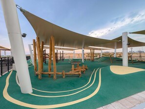 A playground with climbing structures and a green rubberized surface. - Silkhaus NEW Luxurious 1BR in Yas Golf Collection (Abu Dhabi)