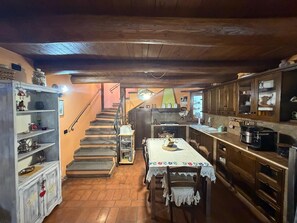 Eine rustikale Küche mit Holzschränken, einem Esstisch mit Spitzenbeschichtung und einer Treppe zu einer oberen Ebene.