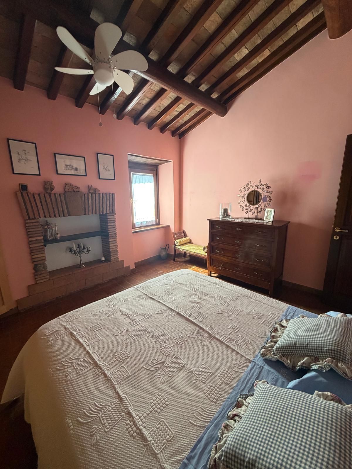 Un dormitorio con cama, cómoda, ventana y ventilador de techo.