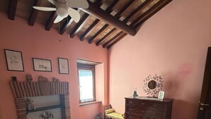 A bedroom with a bed, a dresser, a window, and a ceiling fan. - Quaint 1-bedroom house in lovely Sugano perfect for relaxing stays (Sugano)
