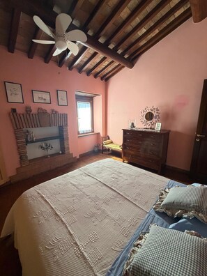 Ein Schlafzimmer mit einem Bett, einem Schminktisch, einem Fenster und einem Deckenventilator.