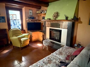 Ein gemütliches Wohnzimmer mit Kamin, Fernseher und einer bequemen Couch.