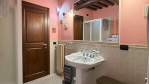 A bathroom with a wooden ceiling, a white sink, a mirror, and a wicker basket. - Quaint 1-bedroom house in lovely Sugano perfect for relaxing stays (Sugano)