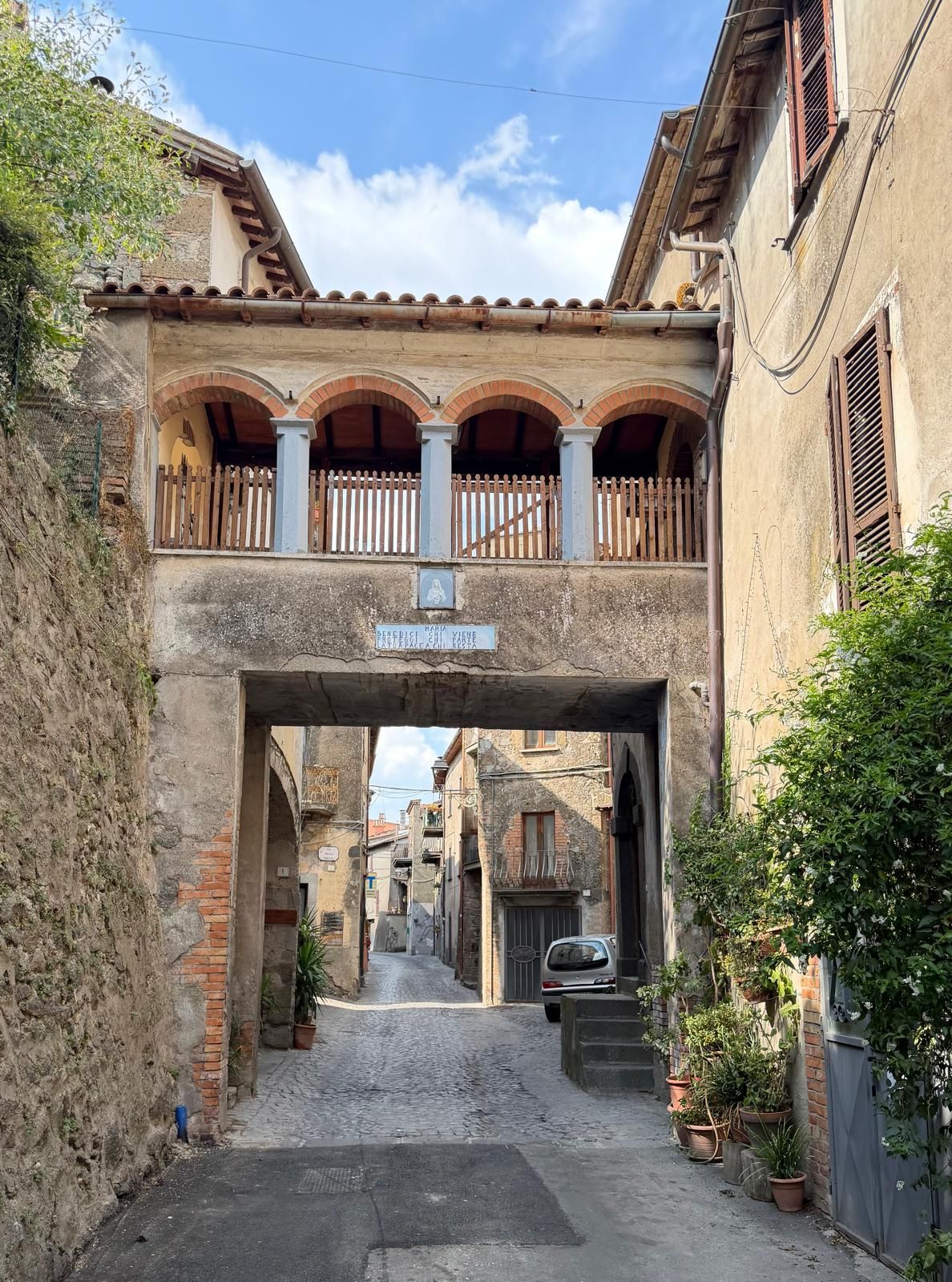 Una calle estrecha con un pasaje cubierto, paredes de piedra y un letrero que indica un restaurante.
