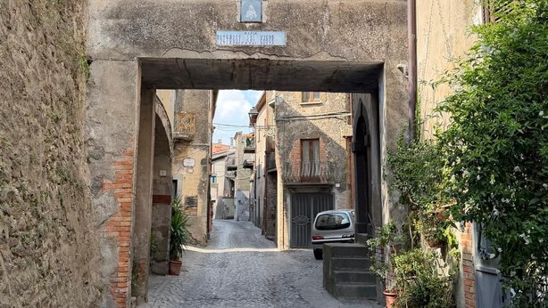 A narrow street with a covered passageway, stone walls, and a sign indicating a restaurant. - Quaint 1-bedroom house in lovely Sugano perfect for relaxing stays (Sugano)