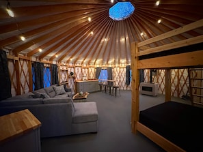 A yurt interior with a sofa, dining area, and a bunk bed. - The Cupsuptic Glamping Yurt in Bethel, Maine (Bethel)