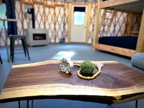 A room with a wooden table, a small stool, and a couch. - The Cupsuptic Glamping Yurt in Bethel, Maine (Bethel)