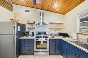Una cucina moderna con frigorifero in acciaio inossidabile, forno a incasso, microonde e pensili in legno.