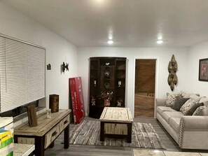 Ein Wohnzimmer mit Sofa, Couchtisch, Fernseher und Schrank.