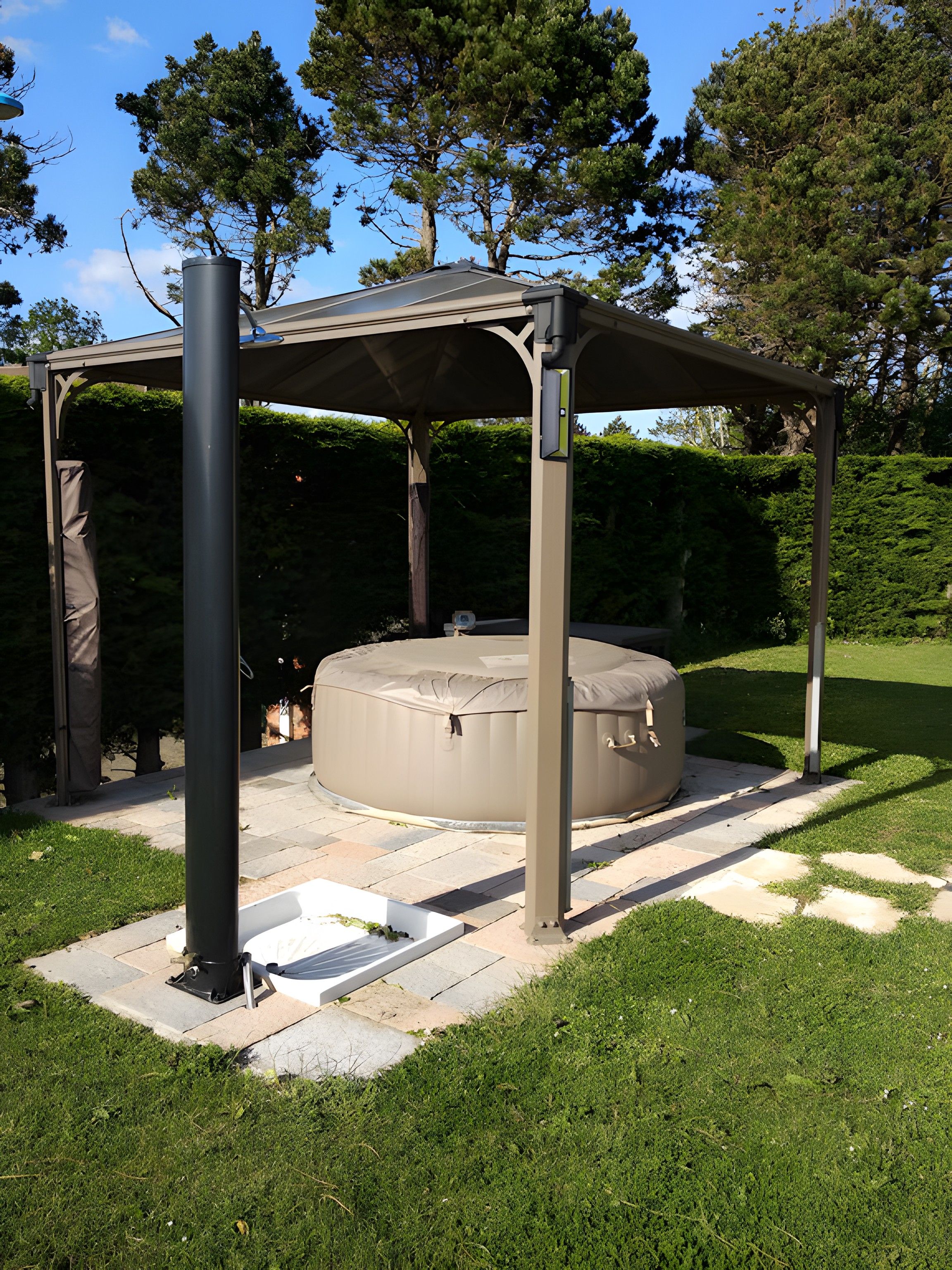 A covered outdoor seating area with a hot tub, surrounded by a garden with a pergola structure.