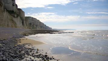 A coastal landscape with a rocky beach, cliffs, and a calm sea.