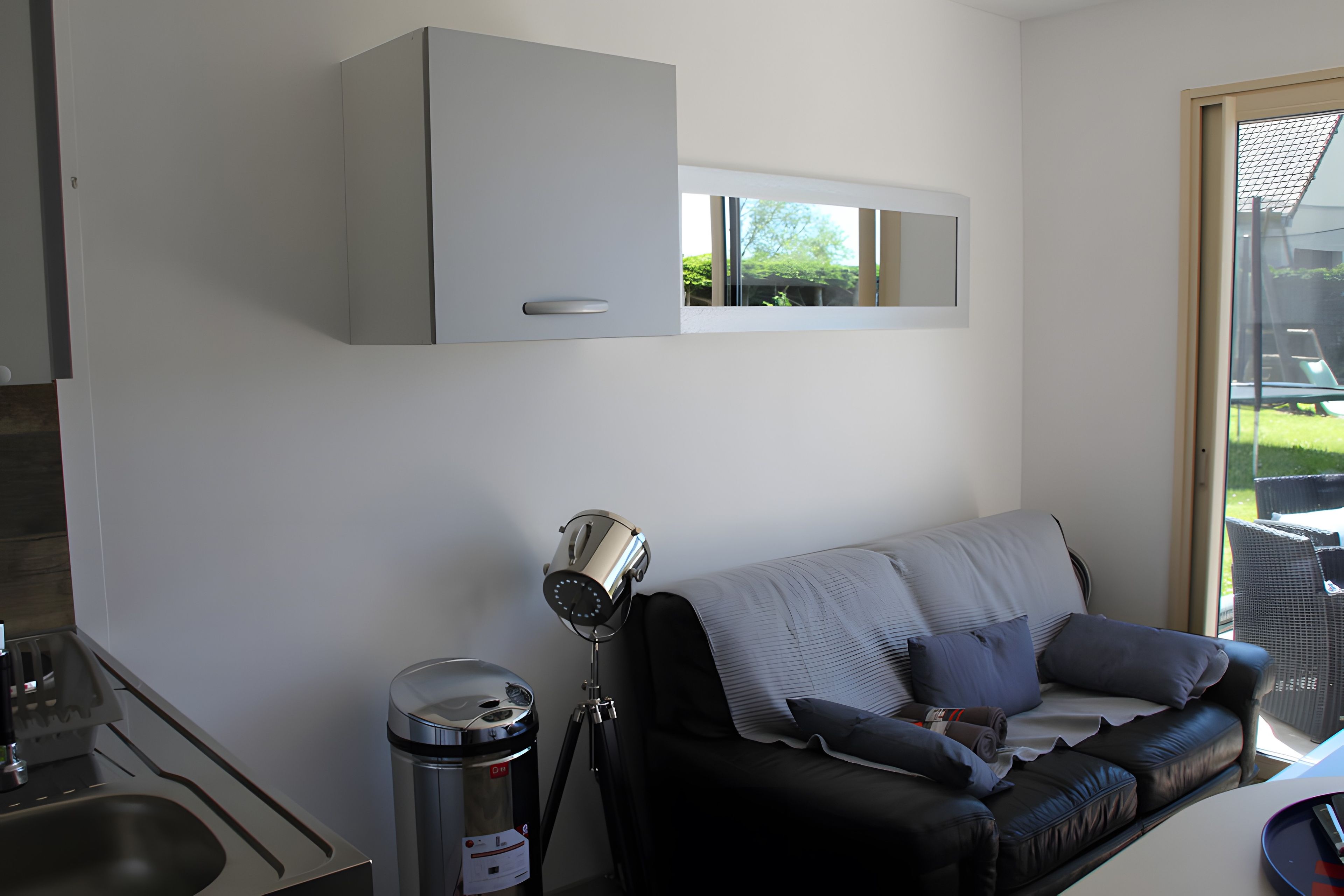 Een moderne woonkamer met een bank, een telescoop en een prullenbak.