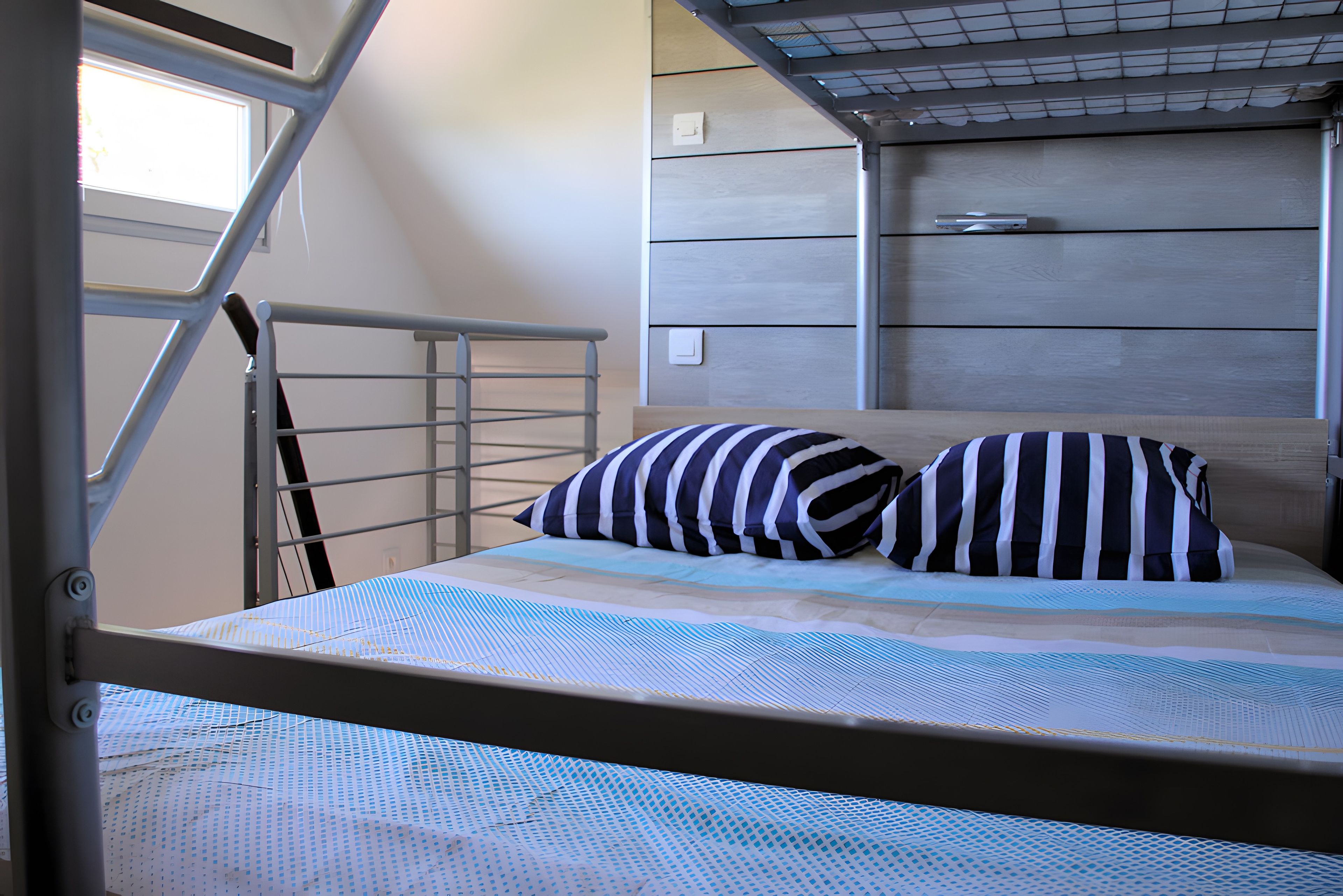 A bunk bed with a metal ladder, a striped pillow, and a patterned bedspread.