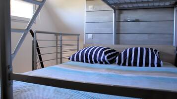 A bunk bed with a metal ladder, a striped pillow, and a patterned bedspread.