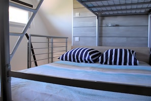 A bunk bed with a metal ladder, a striped pillow, and a patterned bedspread.