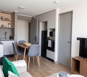 Eine moderne Küche mit Essbereich, einem eingebauten Backofen und einem Fernseher auf einem Holzbodenständer.