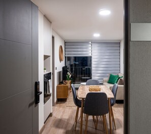 A modern kitchen with built-in appliances, a dining area with a wooden table and chairs, and a view of the outside through a glass door. - Sento Jofre Santiago by Domus Travels (Santiago)