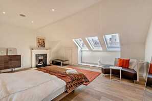 Une chambre moderne avec un grand lit, une cheminée, un canapé et des fenêtres de toit.