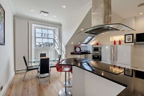 Une cuisine moderne dotée d’un îlot central en verre, de meubles blancs et offrant une vue sur la ville.