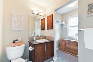Un baño con inodoro, lavamanos, espejo y armarios de madera.