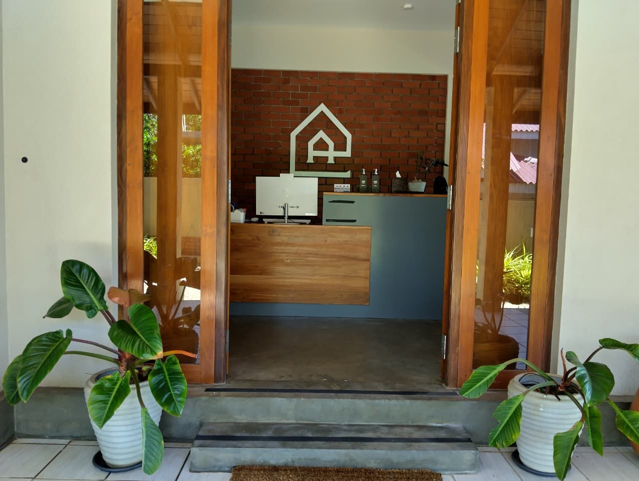 A modern kitchen with a central island, a brick wall, and a logo on the wall.