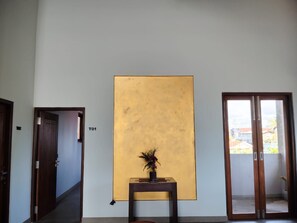A hallway with a large yellow wall, a door labeled 'T01', and a window with a view of buildings.
