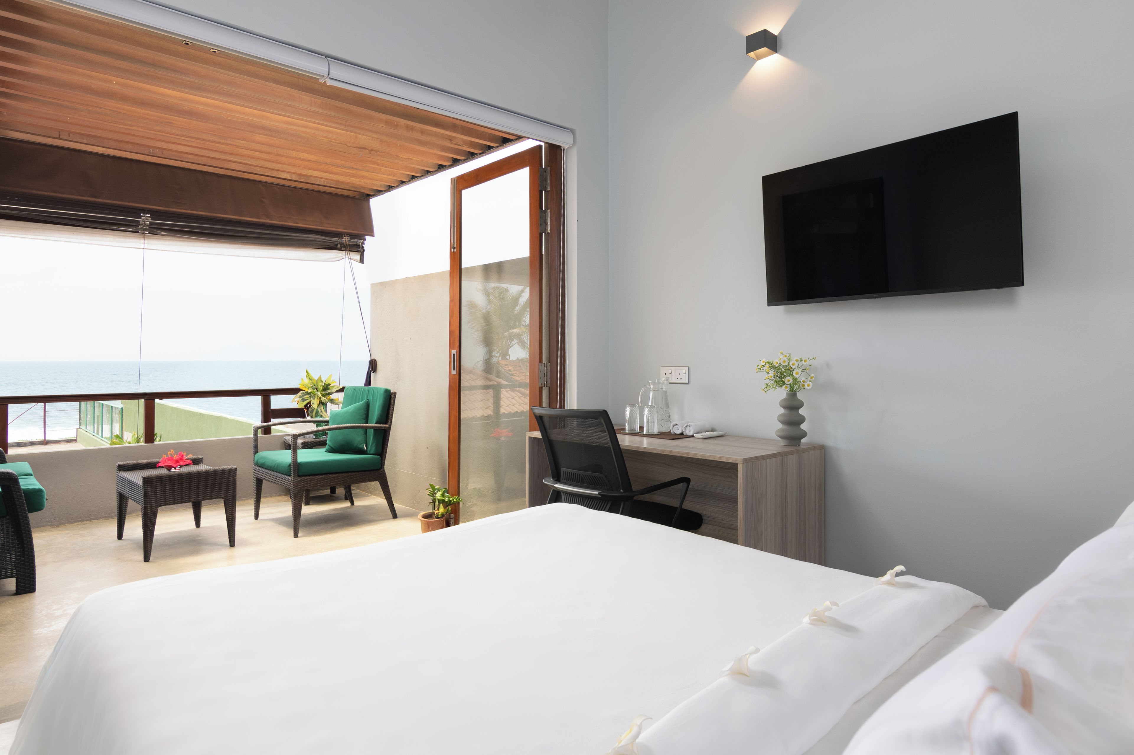 Une chambre d’hôtel avec un lit, un bureau, une chaise, une télévision et une vue sur la mer.