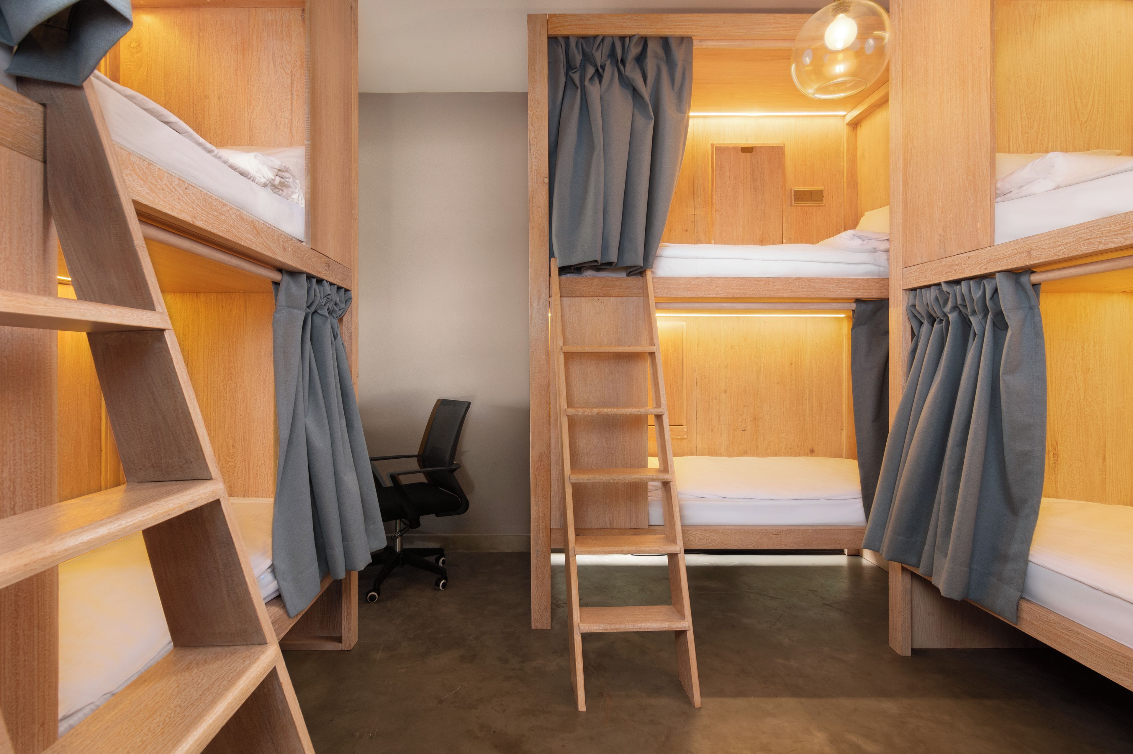 A bunk bed room with a ladder, wooden shelves, and a desk with a chair.