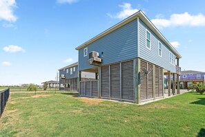 A two-story residential building with a flat roof, large windows, and a covered patio area. - Blue Lobster Lodge | Beach Hair, Zero Cares (Bolivar Peninsula)