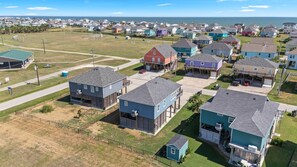 A residential area with houses, a road, and a grassy field. - Blue Lobster Lodge | Beach Hair, Zero Cares (Bolivar Peninsula)