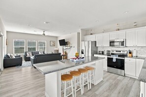 Une cuisine moderne avec des armoires blanches, un comptoir en granit et un four encastré.