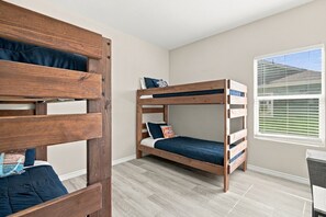 A room with two bunk beds, a window with blinds, and a light-colored floor. - Blue Lobster Lodge | Beach Hair, Zero Cares (Bolivar Peninsula)