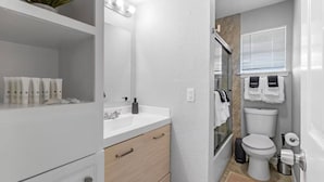 Une salle de bain moderne avec un meuble-lavabo blanc, un miroir, un évier et des toilettes.