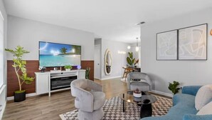 Un salon moderne avec un téléviseur à écran plat, un canapé gris, un canapé bleu et une table basse.