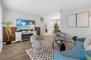 Uma sala de estar moderna com televisão de tela plana, um sofá cinza, um sofá azul e uma mesa de centro.