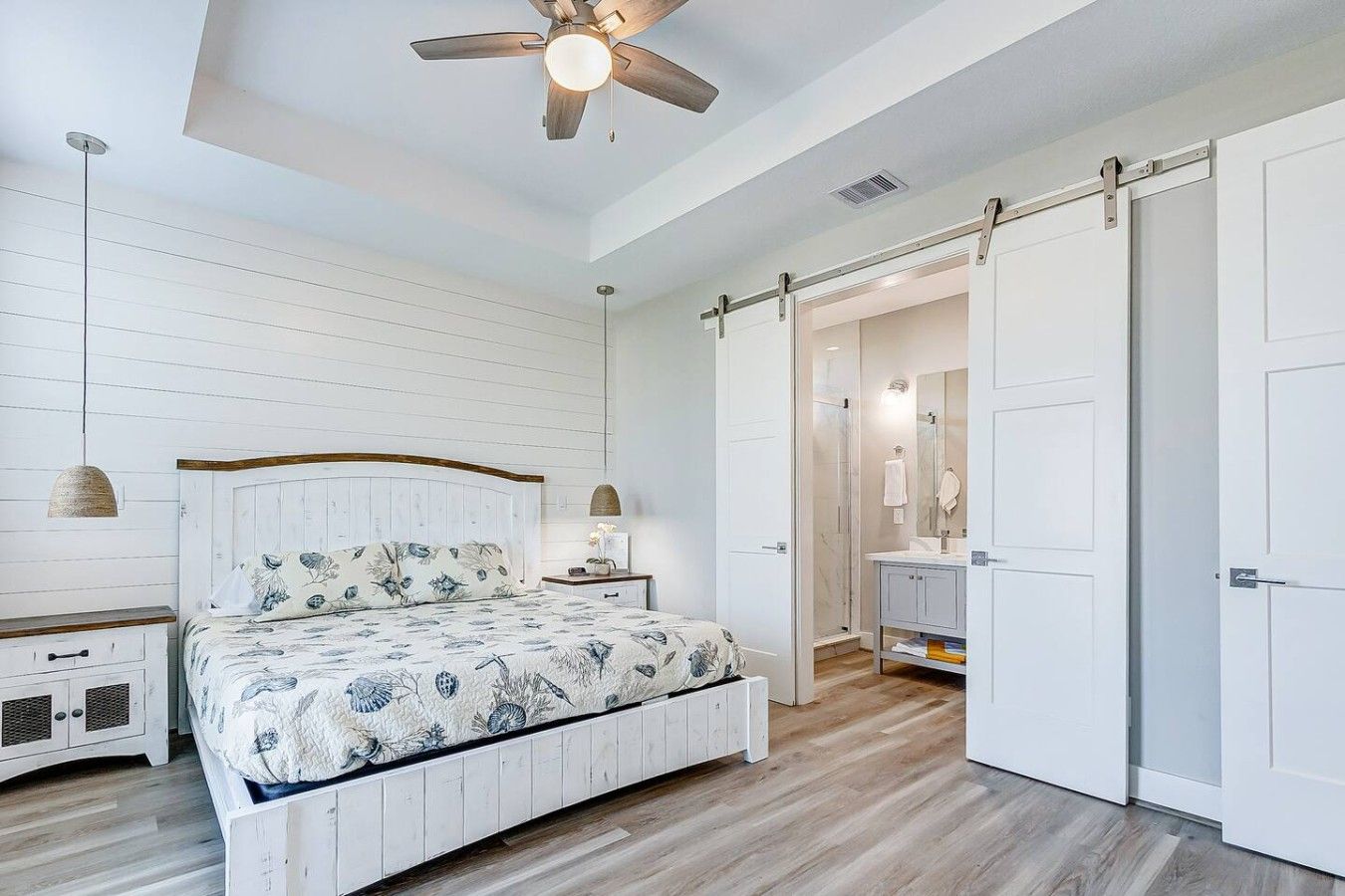A bedroom with a wooden bed, a ceiling fan, a nightstand, and a walk-in closet.