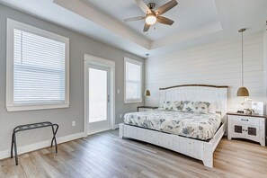 A bedroom with a bed, a ceiling fan, a nightstand, and a window with blinds. - Royal Beach Retreat | Sleeps 16 | 4Bd/2.5Bth (Bolivar Peninsula)