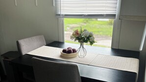 A dining table with chairs, a vase with flowers, and a bowl of food. - Cozy cottage cabin with lake and beach access (Albion)