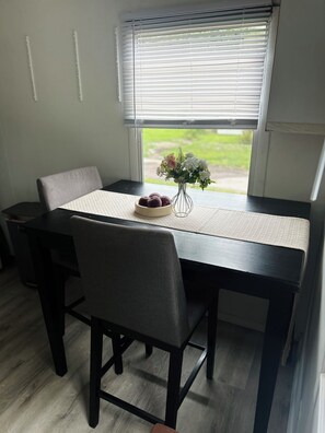 A dining table with chairs, a vase with flowers, and a bowl of food.
