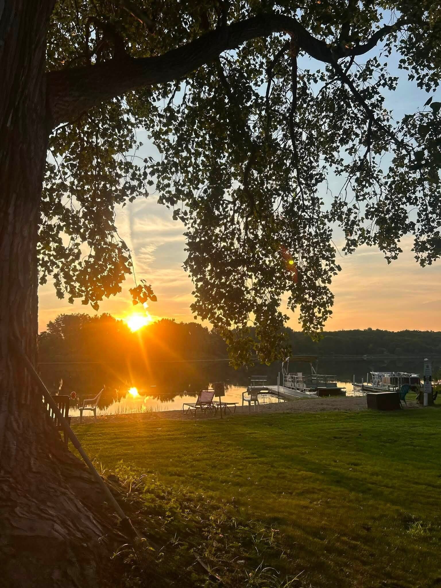 En vacker utsikt över sjön med en brygga, stolar och en gräsyta.