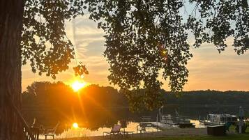 En vacker utsikt över sjön med en brygga, stolar och en gräsyta.