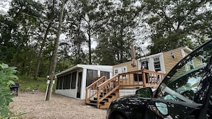 A modern house with a gravel driveway, a wooden staircase, and a black car parked in front.