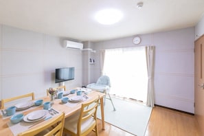 A dining area with a table set for two, a television, and a baby high chair. - Mizuto no Ya, 6th Floor, Unit 6001 (Chuo-ku, Osaka)