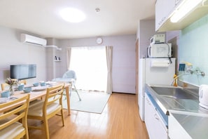 Een kleine keuken met een eethoek, een kinderstoel en een televisie.