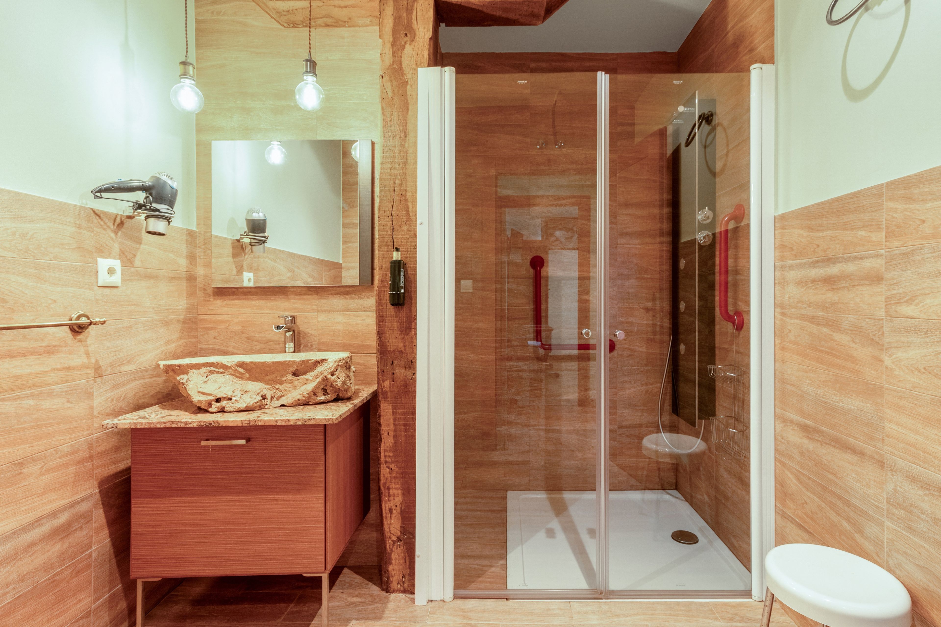 Un baño moderno con tocador de madera, cabina de ducha de vidrio y inodoro blanco.