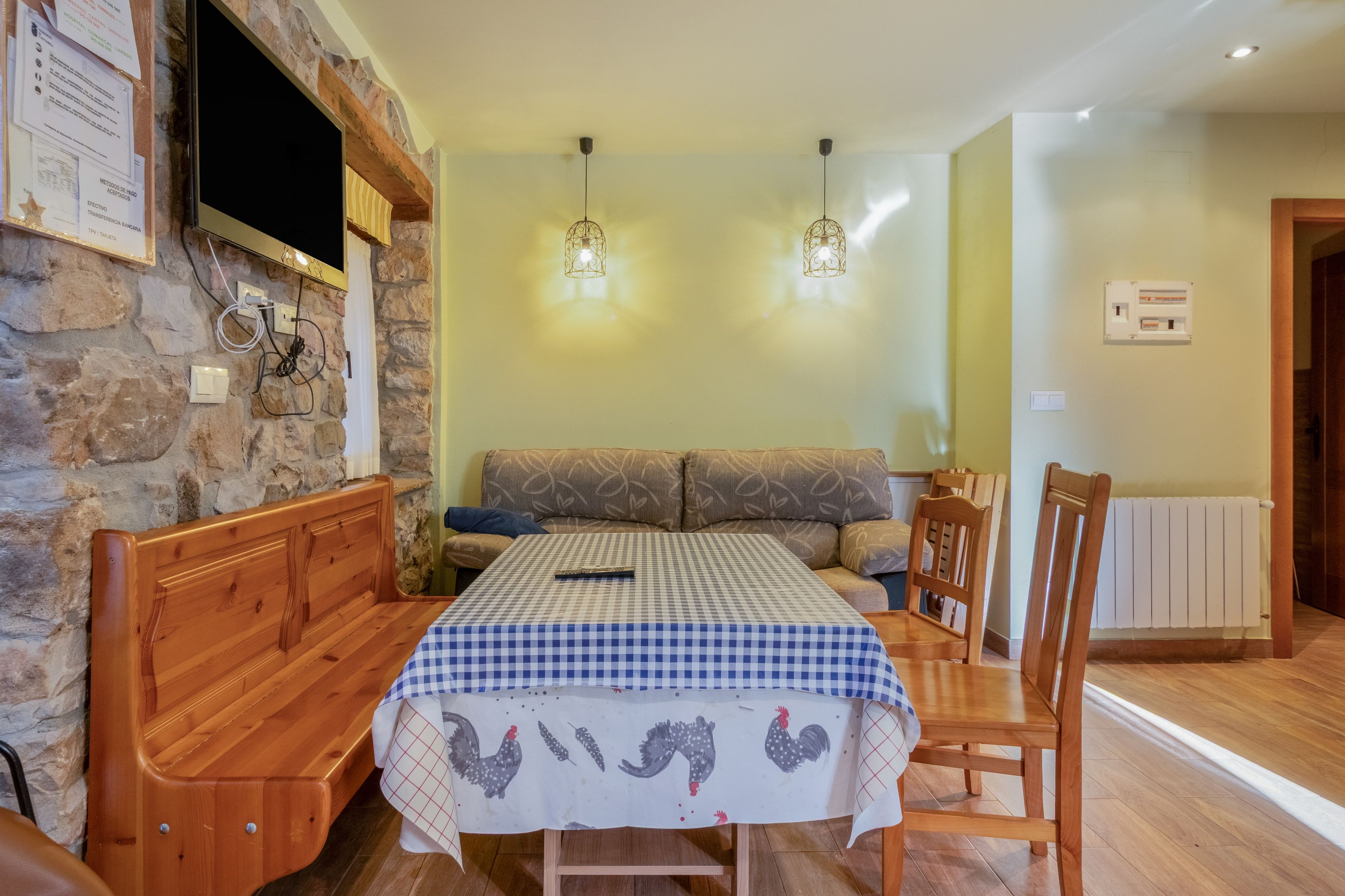 Un comedor con mantel a cuadros, muebles de madera y pared de piedra.