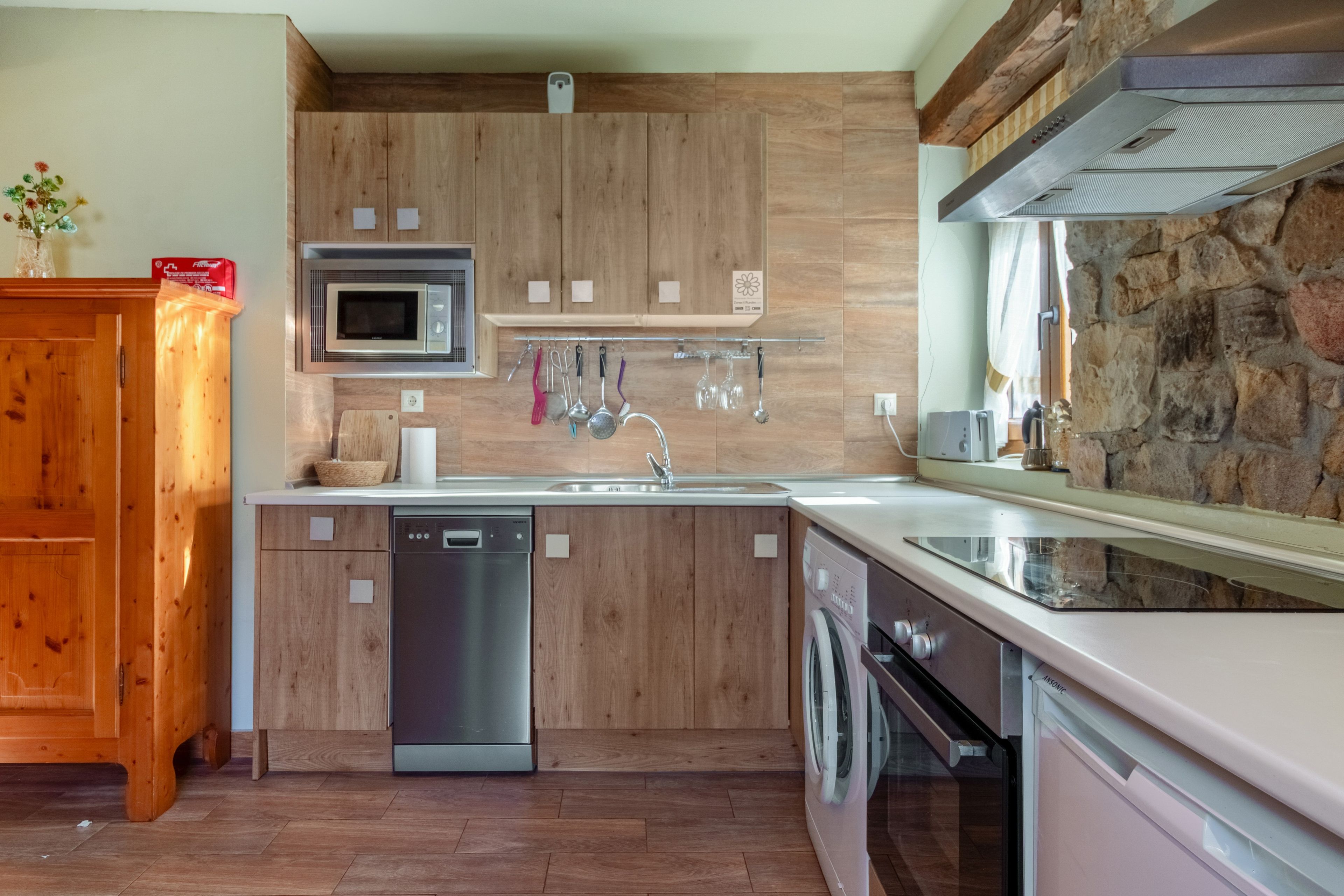 Una cocina moderna con armarios de madera, electrodomésticos de acero inoxidable y una pared de piedra.