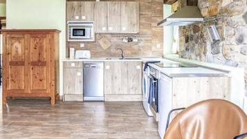 Una cocina moderna con armarios de madera, microondas integrado y una pared decorativa de piedra.